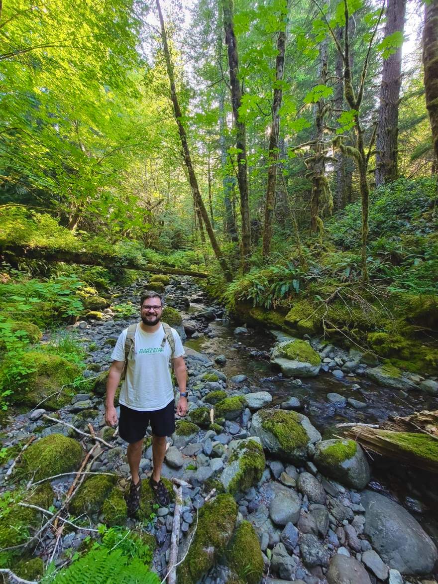 Francis Hall standing in a creek bed in a Vancouver Island forest
